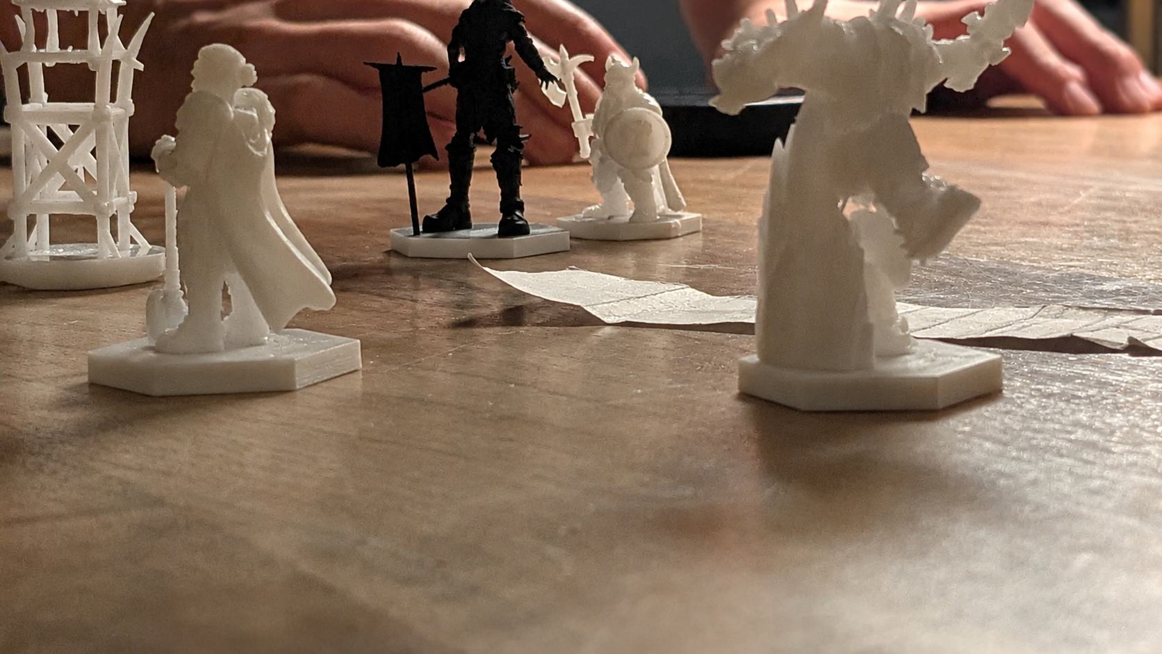 Mehrere unbemalte Warconicas-Miniaturen in Kampfaufstellung auf einem Holztisch